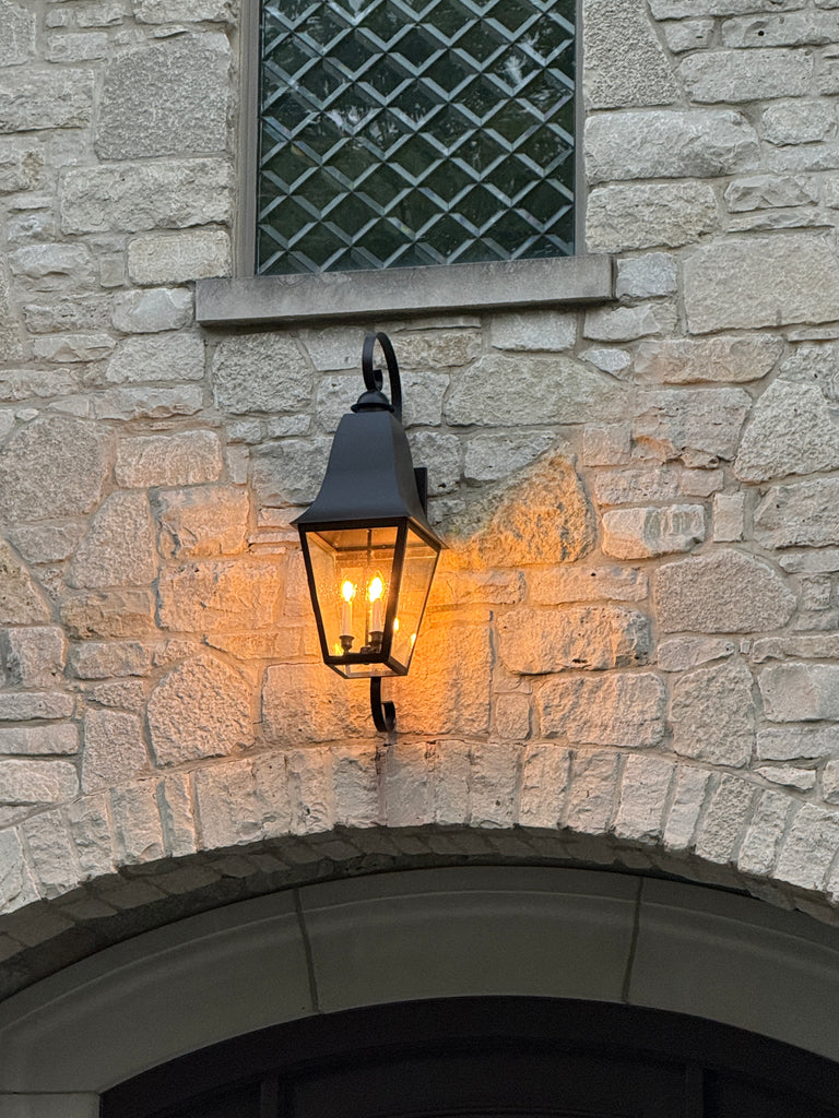 Wall-mounted outdoor light fixture on a stone wall
